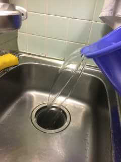 大量の水を排水口に注ぎ入れる